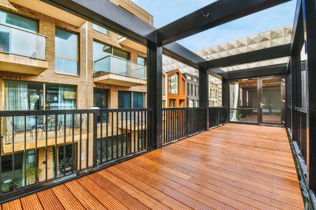 Balkonsanierung Fürth – überdachter Balkon mit Holzbelag (Holzdielen) und schwarzem Metallgeländer